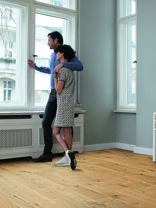 Liebespaar am Fenster in einer Wohnung mit Parkettboden