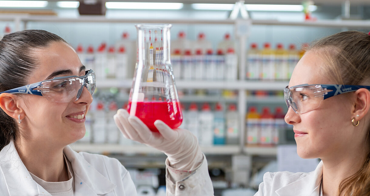 Lacklaboranten im Labor mischen etwas in einem Glas